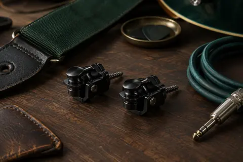 Paire d’attaches de sangle noires à double verrouillage posées près d’une sangle et d’un câble sur un établi