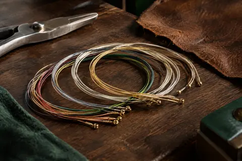 Jeu de cordes classiques Pro-Arté Carbon disposé sur un établi en bois sombre, avec des teintes variées.