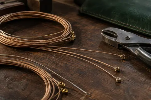 Cordes de guitare acoustique en bronze phosphoreux disposées sur un établi en bois sombre