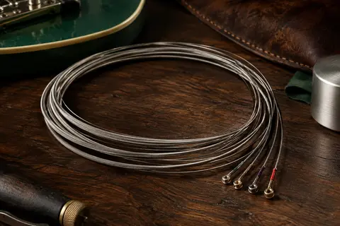 Jeu de cordes métalliques Ernie Ball Slinky Cobalt posé sur un établi de musicien en bois sombre