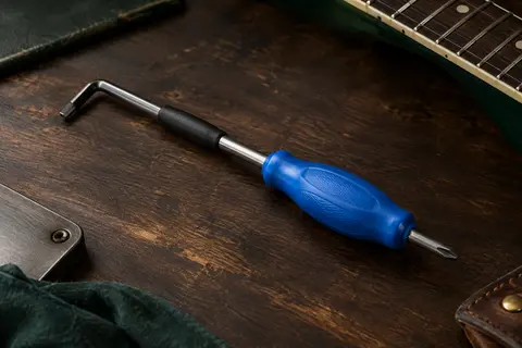 Clé de truss rod Music Nomad bleue avec gaine protectrice et tournevis magnétique, posée sur un établi.