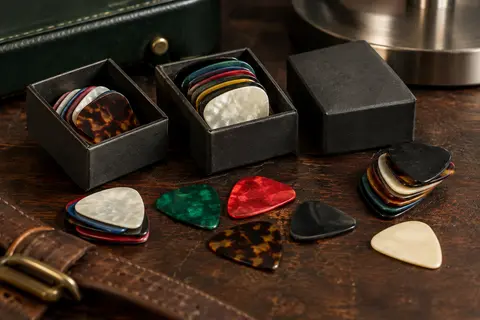 Médiators Picko en celluloïd de plusieurs couleurs et épaisseurs, rangés sur un établi avec leurs boîtes