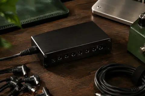 Bloc d’alimentation Strich noir en aluminium posé sur un établi de musicien avec ses connecteurs visibles